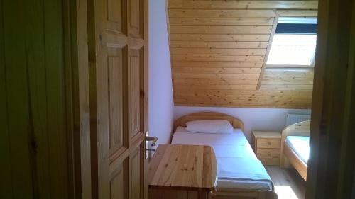 a small bedroom with a bed and a wooden table at Villa Giulia Vendégház in Verpelét