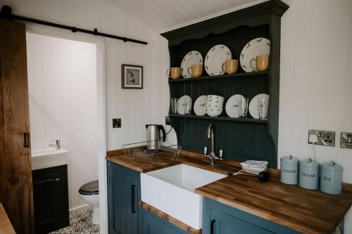 a kitchen with blue cabinets and a sink and a toilet at Angela's Rest Shepherds Hut with Scandi Hot Tub in Boston