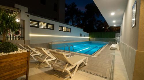 a swimming pool with white chairs and a swimming pool at OPERA SUITES Apart Hotel in Antalya
