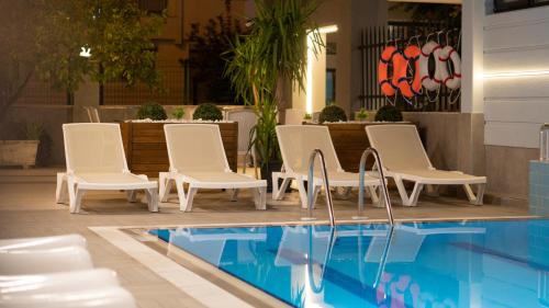 a group of white chairs next to a swimming pool at OPERA SUITES Apart Hotel in Antalya