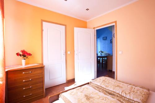カルパチにあるWaldi Pokoje Gościne z aneksemのオレンジ色の壁のベッドルーム1室、ベッド1台、ドレッサーが備わります。