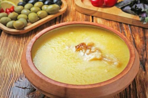 a bowl of soup on a wooden table with fruit at Aragats Hotel in Aragats