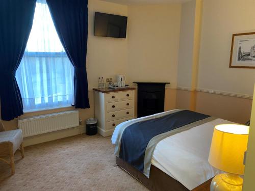 a bedroom with a bed and a dresser and a window at The Pegwell Bay Hotel in Ramsgate