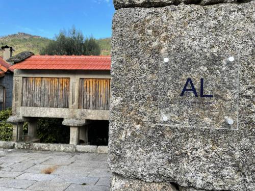 a rock with the word al on it in front of a building at CabrilHome - AL Gerês in Cabril