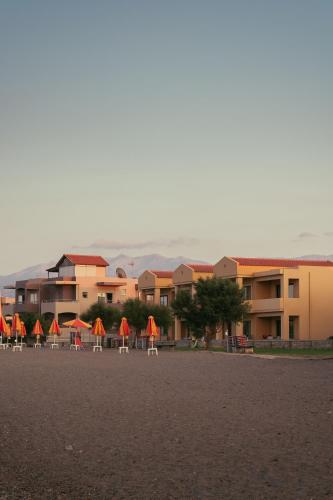 a row of chairs with orange umbrellas in front of a building at Silver Beach Hotel & Apartments in Gerani Chanion