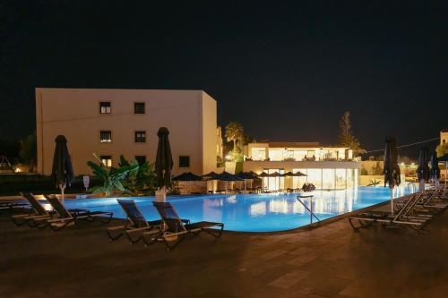 a swimming pool with chairs and a building at night at Silver Beach Hotel & Apartments in Gerani Chanion