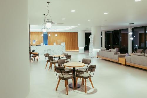 a living room with tables and chairs and a couch at Silver Beach Hotel & Apartments in Gerani Chanion