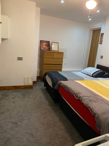 a bedroom with two beds and a dresser in it at Mansion 8 bedrooms in Private Gated Ave Huge garden Hot tub FREE SAUNA up to 23 in Luton