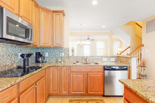 a kitchen with wooden cabinets and a stainless steel refrigerator at Sunset Island - 35 Seaside in Ocean City