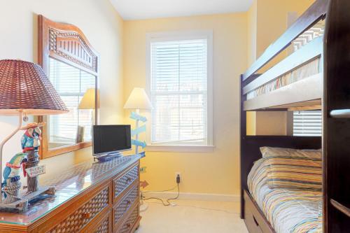 a bedroom with a bunk bed and a desk with a television at Sunset Island - 35 Seaside in Ocean City