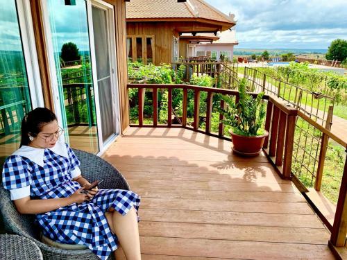 a woman sitting on a porch looking at her cell phone at Sumeru in Sen Monorom