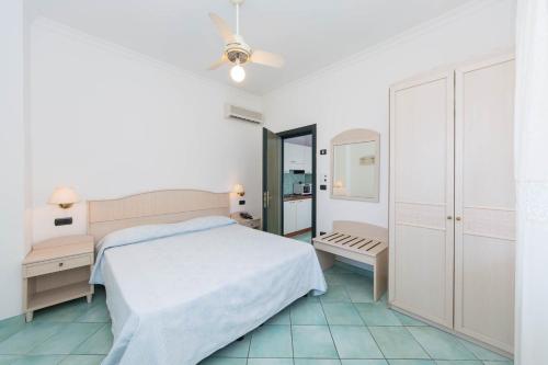 a white bedroom with a bed and a mirror at La Residenza Aparthotel in Maiori