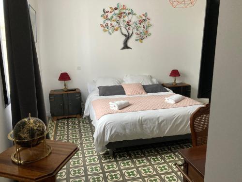 a bedroom with a bed with a tree on the wall at Hôtel La Demeure Coloniale in Moriani Plage