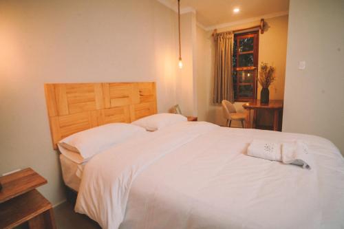 a bedroom with a large white bed with a wooden headboard at KANTU GARDEN LODGE in Moyobamba