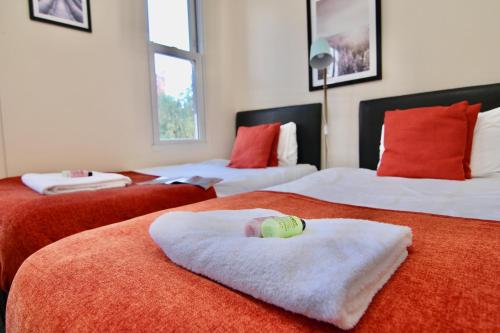 een slaapkamer met 3 bedden en rode en witte dekens bij Charming Studio 2 mins Walk To Belgrade Theatre in Coventry