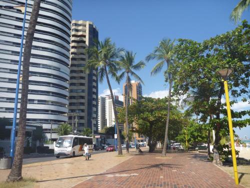 una calle de la ciudad con palmeras y un autobús en Apartamento Atlântico, en Fortaleza
