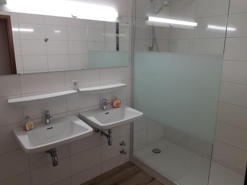 a white bathroom with two sinks and a shower at Hotel Ditzingen in Ditzingen