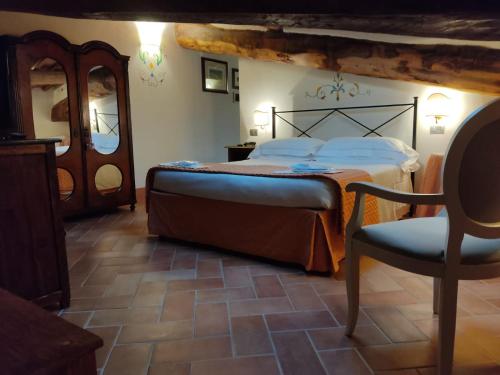 a bedroom with a bed and a chair at Villa Curina Resort in Castelnuovo Berardenga