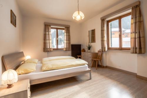 1 dormitorio con 1 cama, escritorio y ventanas en Appartamento Blank, en Arabba