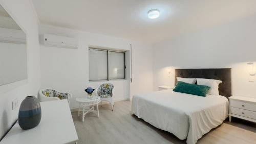 ein weißes Schlafzimmer mit einem Bett und einem Tisch und Stühlen in der Unterkunft City Balcony in Ponta Delgada