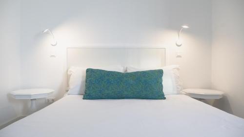 ein weißes Bett mit einem blauen Kissen darauf in der Unterkunft City Balcony in Ponta Delgada
