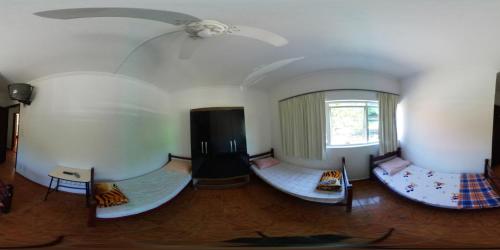 a room with three beds and a ceiling at Hotel Pousada Liberdade in Pindamonhangaba