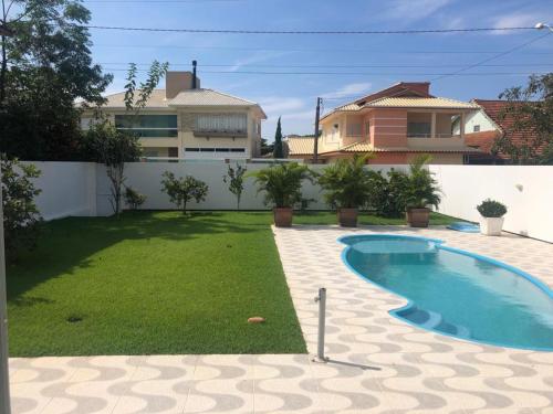 a backyard with a swimming pool and a house at Casa da Lis com Piscina in Palhoça