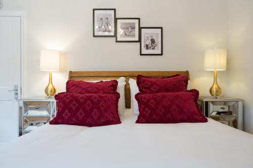 een slaapkamer met een bed met rode kussens en 2 lampen bij The Dog & Gun Inn in Netheravon