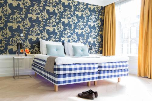 a bedroom with a bed with a blue and gold wallpaper at Amsterdam Canal Hotel in Amsterdam