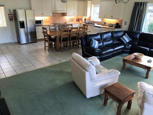 ein Wohnzimmer mit Sofas, einem Tisch und einer Küche in der Unterkunft Bramble Cottage - Luxury Holiday Cottage - 4 Beds 3 Baths - Parking - Beach 1 Mile - Fenced Child & Dog Friendly - EV Chrger in Bude