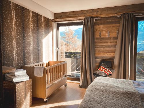 a bedroom with a baby crib and a window at Chalet on the Rood Zell am See Kaprun in Piesendorf