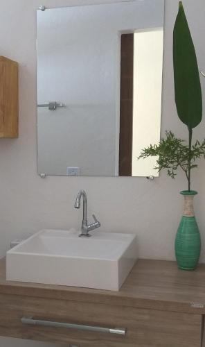 a bathroom sink with a mirror and a vase at Casa Beija-flor Pousada in Ilha de Boipeba