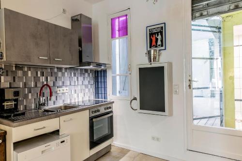 une cuisine avec un évier et une cuisinière dans l'établissement Montmartre Apartments - Androuet, à Paris