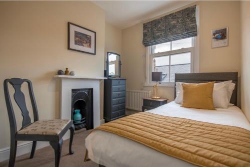 a bedroom with a bed and a chair and a fireplace at Spencer House & 107 & 109 Nunnery Lane in York
