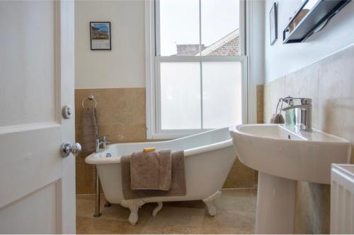 a bathroom with a tub and a sink and a window at Spencer House & 107 & 109 Nunnery Lane in York