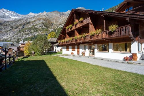 a building with a green lawn next to a mountain at Residence Monterosa in Macugnaga