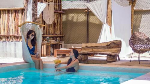 two women sitting in the water in a swimming pool at Jungla y Estrellas in Cobá