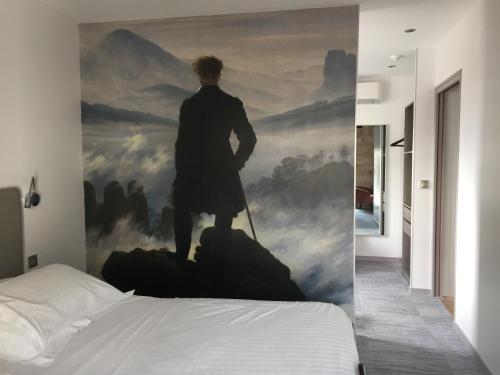 a room with a painting of a man standing on a mountain at Hotel de la Couronne in Aix-les-Bains