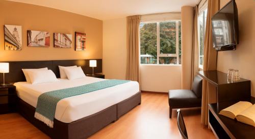 Habitación de hotel con cama y TV en Girasoles Hotel, en Lima