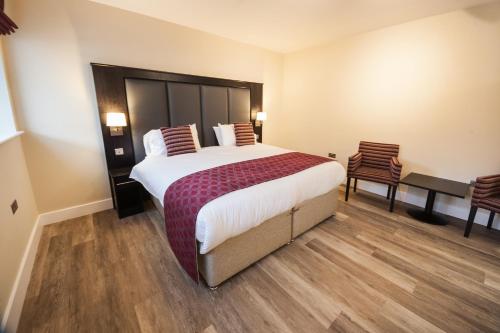 ウィスベックにあるCrown Lodge Hotelの大きなベッドと椅子2脚が備わるホテルルームです。
