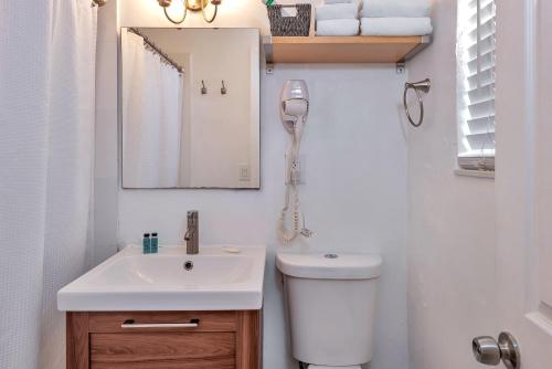 a bathroom with a toilet and a sink and a mirror at Oasis Hotel in Fort Lauderdale