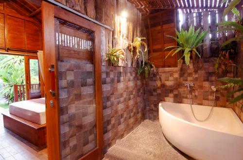 a bathroom with a bath tub and a sink at Kubu Kayana Batuan in Sukawati