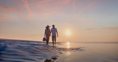two people walking on the beach at sunset at Villa Noordzee in Renesse