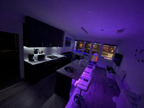cocina con iluminación púrpura y taburetes en una habitación en Treba Malo Odmorit - Family Room, PS4 Pro, Free parking, en Karlovac
