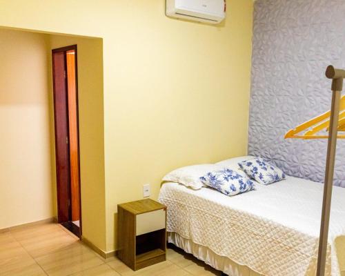 a bedroom with a bed with blue and white pillows at Pousada Estrela da manhã in São Miguel do Gostoso