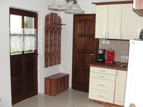 a kitchen with white cabinets and a wooden door at Vörösmál Vendégház in Balatonfüred