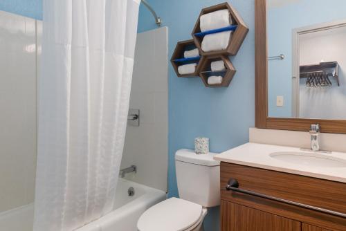 a bathroom with a toilet and a sink and a mirror at HomeTowne Studios by Red Roof Newport News - Hampton West in Newport News