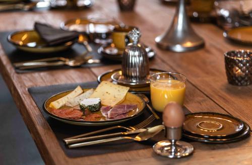 a table with a plate of food and a glass of orange juice at B&B landhuis Hauwaart 80 in Oudenaarde