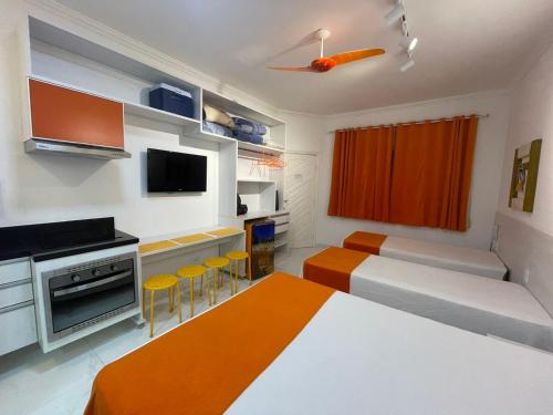 um quarto com 2 camas e uma cozinha com detalhes em laranja em FLAT AMARÍLIS - RIVIERA DE SÃO LOURENÇo em Riviera de São Lourenço