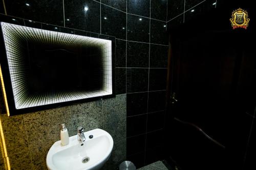 a black tiled bathroom with a sink and a mirror at Rezydencja Bakamus in Sandomierz